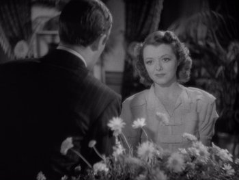 Movie still from “The Young in Heart” (1938), directed by Gilbert Pratt – A man and a woman are standing next to each other in front of flowers; Close Up shot, Over the shoulder angle