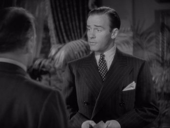 Movie still from “The Young in Heart” (1938), directed by Gilbert Pratt – A man wearing a suit and tie talking to another man; Medium shot, Over the shoulder angle