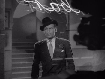 Movie still from “The Young in Heart” (1938), directed by Gilbert Pratt – A black and white photo of a man in a suit and hat; Medium shot, High angle