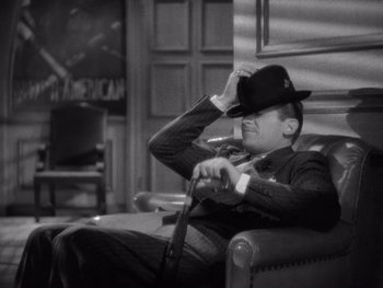 Movie still from “The Young in Heart” (1938), directed by Gilbert Pratt – A black and white photo of a man wearing a hat; Medium shot, High angle