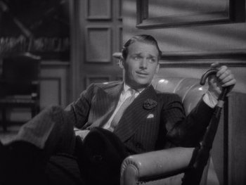 Movie still from “The Young in Heart” (1938), directed by Gilbert Pratt – A man in a suit sitting in a chair; Medium shot, High angle