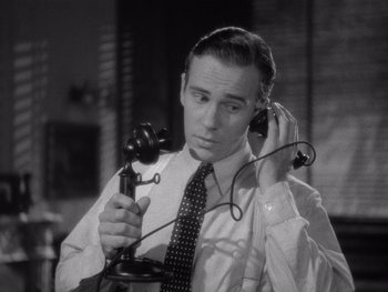 Movie still from “The Young in Heart” (1938), directed by Gilbert Pratt – A black and white photo of a man holding a phone; Close Up shot, High angle