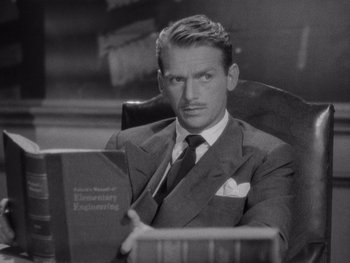 Movie still from “The Young in Heart” (1938), directed by Gilbert Pratt – A man in a suit and tie sitting in an office chair; Medium shot, High angle