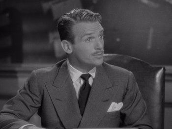 Movie still from “The Young in Heart” (1938), directed by Gilbert Pratt – A man wearing a suit and tie sitting at a table; Close Up shot, High angle