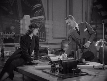 Movie still from “The Young in Heart” (1938), directed by Gilbert Pratt – A man and a woman sitting at a desk; Medium shot, High angle