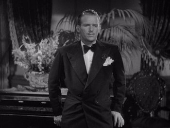 Movie still from “The Young in Heart” (1938), directed by Gilbert Pratt – A man in a tuxedo standing in front of a plant; Medium shot, Low angle
