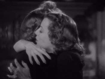 Movie still from “The Young in Heart” (1938), directed by Gilbert Pratt – A woman hugging another woman in a room; Medium shot, Over the shoulder angle