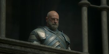 Movie still from “House of the Dragon” (2022), created by George R.R. Martin – A man with a beard wearing a suit of armor; Medium shot, Low angle