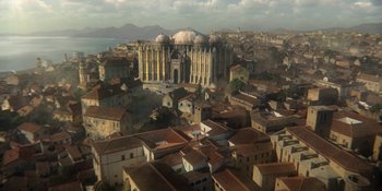 Movie still from “House of the Dragon” (2022), created by George R.R. Martin – An aerial view of an old town with a large building in the background; Extreme Wide shot, High angle