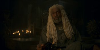 Movie still from “House of the Dragon” (2022), created by George R.R. Martin – A man with dreads is sitting in a chair; Medium shot, Low angle
