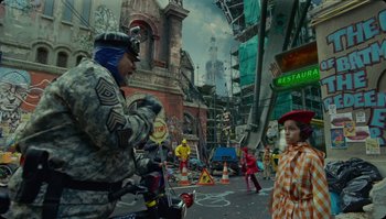 Movie still from “The Zero Theorem” (2013), directed by Terry Gilliam – A man in a uniform riding a motorcycle down a street; Wide shot, Over the shoulder angle