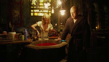 Movie still from “The Zero Theorem” (2013), directed by Terry Gilliam – A man and a woman working in a room; Medium shot, Low angle