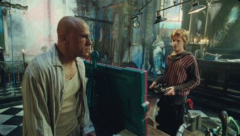 Movie still from “The Zero Theorem” (2013), directed by Terry Gilliam – A man and a woman are standing in front of a computer monitor; Medium shot, Low angle