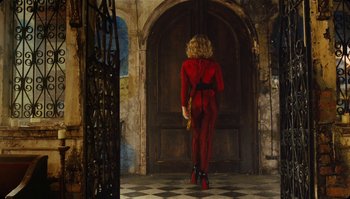 Movie still from “The Zero Theorem” (2013), directed by Terry Gilliam – A woman in a red catsuit is standing in front of a door; Wide shot, Low angle