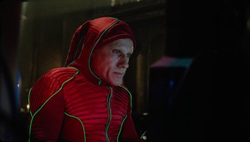 Movie still from “The Zero Theorem” (2013), directed by Terry Gilliam – A man in a red jacket is looking at a computer screen; Medium shot, Low angle