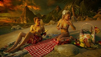 Movie still from “The Zero Theorem” (2013), directed by Terry Gilliam – A man and a woman sitting on a blanket on the beach; Wide shot, High angle
