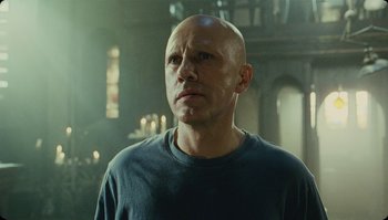 Movie still from “The Zero Theorem” (2013), directed by Terry Gilliam – A man with bald head looking to his left; Close Up shot, Low angle