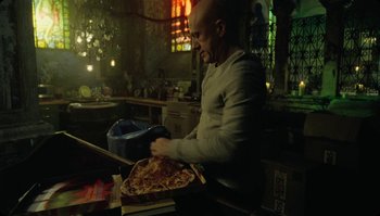 Movie still from “The Zero Theorem” (2013), directed by Terry Gilliam – A man is holding a large piece of pizza; Medium shot, High angle