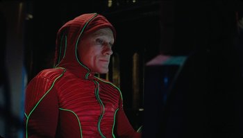 Movie still from “The Zero Theorem” (2013), directed by Terry Gilliam – A man in a red outfit looking at a computer screen; Medium shot, Low angle