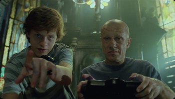 Movie still from “The Zero Theorem” (2013), directed by Terry Gilliam – A man and a boy are playing a video game together; Close Up shot, Low angle