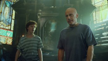 Movie still from “The Zero Theorem” (2013), directed by Terry Gilliam – Two people standing in a room with a painting in the background; Medium shot, Over the shoulder angle