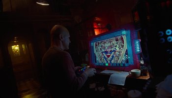 Movie still from “The Zero Theorem” (2013), directed by Terry Gilliam – A bald man playing a video game on a television; Medium shot, High angle