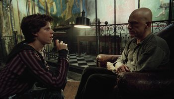 Movie still from “The Zero Theorem” (2013), directed by Terry Gilliam – A man and a woman sitting on a couch; Medium shot, Over the shoulder angle