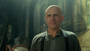 Movie still from “The Zero Theorem” (2013), directed by Terry Gilliam – A bald man wearing suspenders standing in front of a building; Close Up shot, Low angle