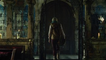 Movie still from “The Zero Theorem” (2013), directed by Terry Gilliam – A woman walking down a hall way with a backpack; Wide shot, Low angle
