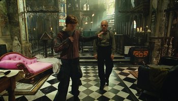 Movie still from “The Zero Theorem” (2013), directed by Terry Gilliam – Two men are standing in a room with black and white checkered floors; Wide shot, High angle