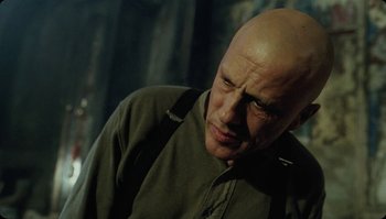 Movie still from “The Zero Theorem” (2013), directed by Terry Gilliam – A man with bald head looking down at the ground; Close Up shot, Low angle