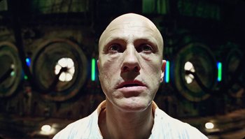 Movie still from “The Zero Theorem” (2013), directed by Terry Gilliam – A man with bald head looking into the camera; Close Up shot, Low angle