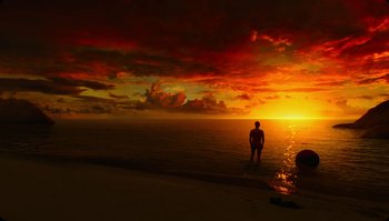 Movie still from “The Zero Theorem” (2013), directed by Terry Gilliam – A man standing on a beach at sunset; Extreme Wide shot, Low angle