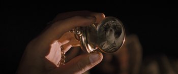 A person holding a pocket watch with a picture of a woman in it