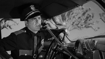 Movie still from “Them!” (1954), directed by Gordon Douglas – A police officer sitting in a car with a child in the back seat; Medium shot, Low angle