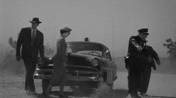 Movie still from “Them!” (1954), directed by Gordon Douglas – An old photo of two men and a woman standing next to an old car; Wide shot, Low angle