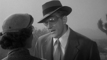 Movie still from “Them!” (1954), directed by Gordon Douglas – An old photo of a man in a suit and hat talking to a woman; Close Up shot, Over the shoulder angle