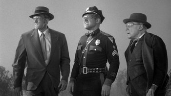 Movie still from “Them!” (1954), directed by Gordon Douglas – A black and white photo of three men in uniform; Medium shot, Low angle