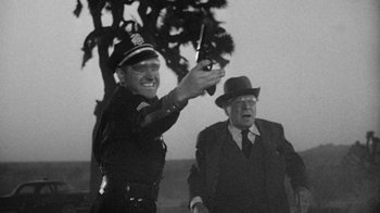 Movie still from “Them!” (1954), directed by Gordon Douglas – A police officer and a man in a suit and tie; Medium shot, Low angle