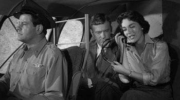 Movie still from “Them!” (1954), directed by Gordon Douglas – A man and a woman on a cell phone in an airplane; Medium shot, Low angle