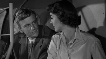 Movie still from “Them!” (1954), directed by Gordon Douglas – A man and a woman sitting next to each other in front of each other; Medium shot, Over the shoulder angle