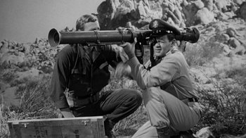 Movie still from “Them!” (1954), directed by Gordon Douglas – A man holding a gun while sitting next to another man; Medium shot, Low angle