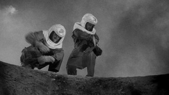 Movie still from “Them!” (1954), directed by Gordon Douglas – Two men in spacesuits are climbing up a hill; Wide shot, Low angle