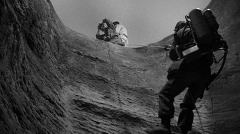 Movie still from “Them!” (1954), directed by Gordon Douglas – A man is climbing up the side of a mountain; Wide shot, Low angle