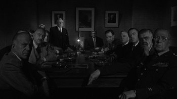 Movie still from “Them!” (1954), directed by Gordon Douglas – A black and white photo of a group of people sitting at a table; Wide shot, High angle