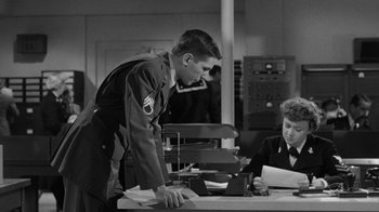 Movie still from “Them!” (1954), directed by Gordon Douglas – A man in uniform standing in front of a table; Medium shot, Over the shoulder angle
