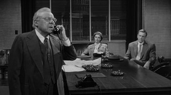 Movie still from “Them!” (1954), directed by Gordon Douglas – An older man talking on the phone in front of two other people; Medium shot, High angle