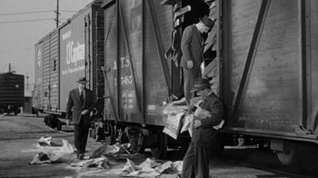 Movie still from “Them!” (1954), directed by Gordon Douglas – A black and white photo of men standing next to a train car; Wide shot, Low angle