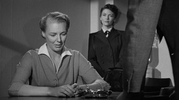 Movie still from “Them!” (1954), directed by Gordon Douglas – A woman sitting at a table in front of another woman in a suit; Medium shot, Over the shoulder angle