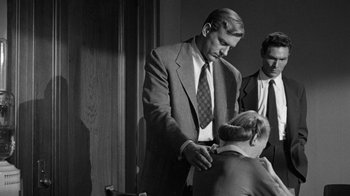 Movie still from “Them!” (1954), directed by Gordon Douglas – A black and white photo of a man in a suit and tie; Medium shot, Over the shoulder angle